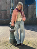 model op straat met lichtblauwe barrel jeans en roze jacket